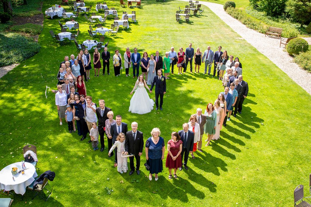 Gruppenfoto in Herzform mit dem Hochzeitspaar in der Mitte